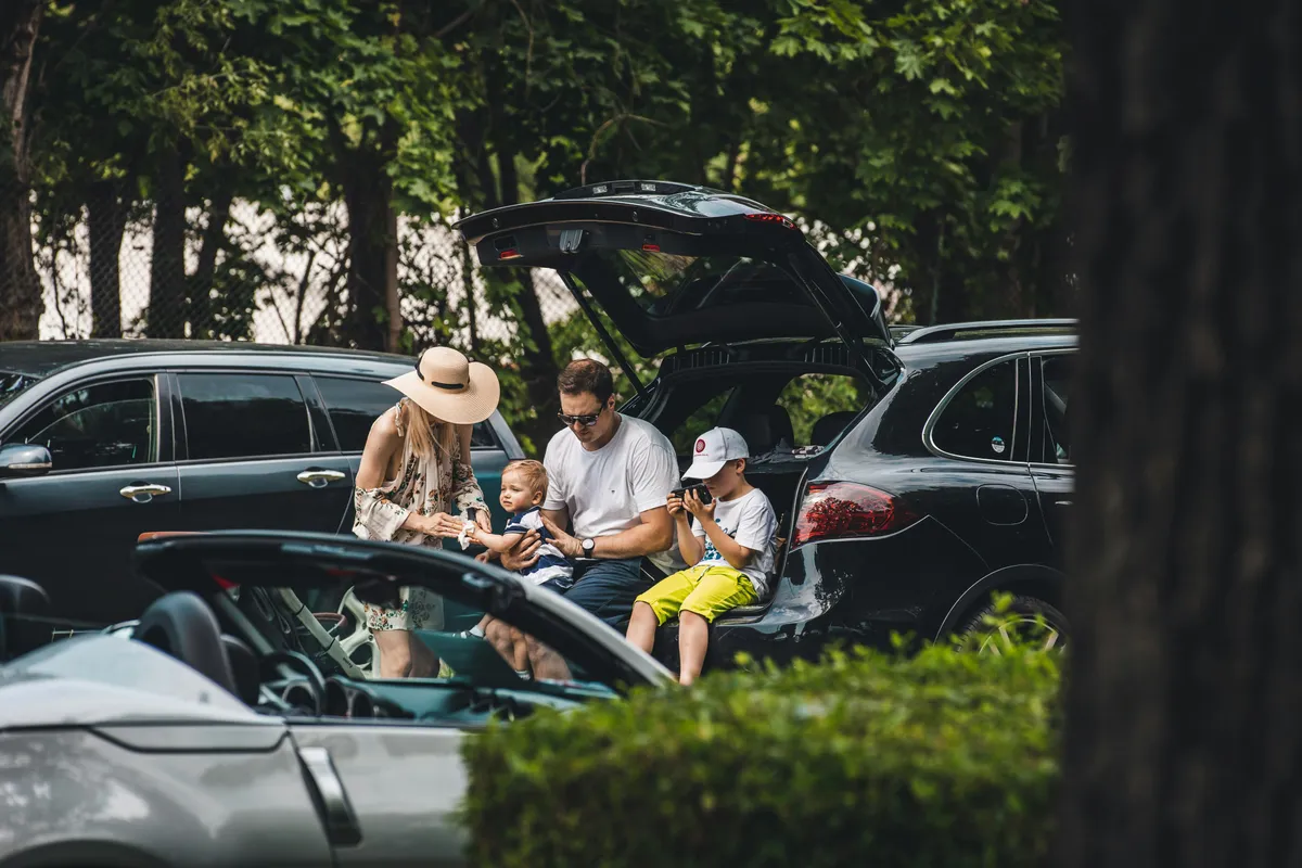 familia sentada na mala de um carro estacionado num parque